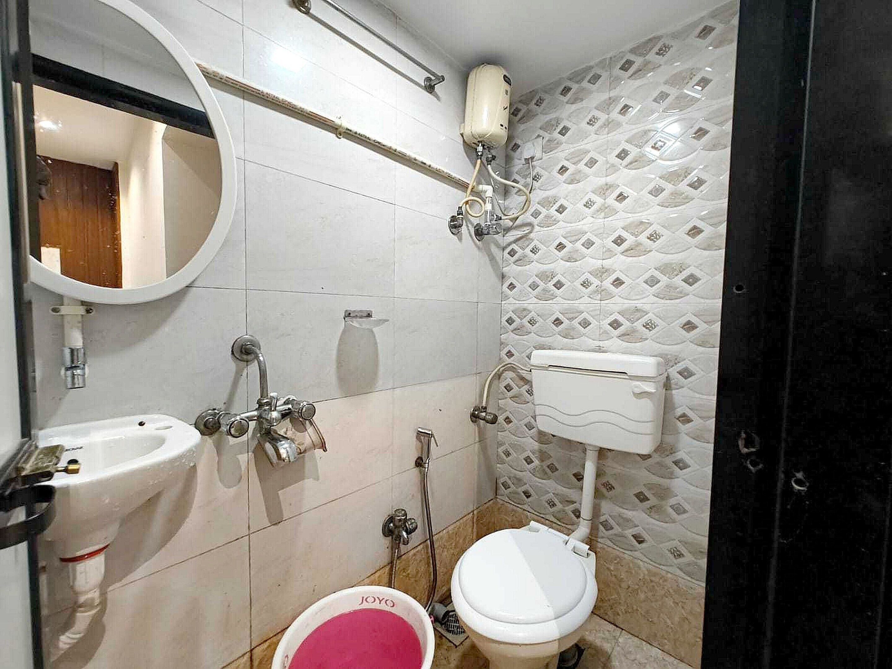 A bathroom with a toilet, bidet, sink, and mirror.