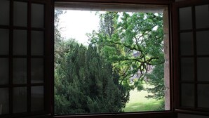 Une pièce dotée d’une grande fenêtre donnant sur une forêt dense et sur un bâtiment situé au loin.