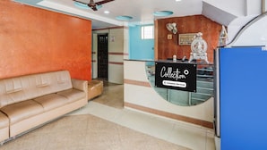 A reception area with a sofa, a reception desk, a ceiling fan, and a statue. - Classic With Twin Bed Hotel Rama Royal (Nellore)