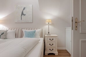A bedroom with a bed, bedside table, lamp, and a wall-mounted artwork. - Wencke - Westerland (Westerland)