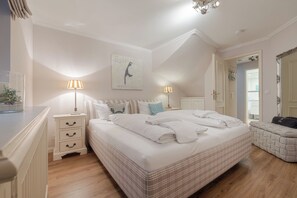 Une chambre à coucher avec un lit, des tables de chevet, des lampes, un tableau, un miroir et une porte.