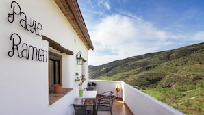 A balcony with a table and chairs, a potted plant, and a sign reading 'Padre Ramon.' - Rural Cottage for a Romantic Retreat (Laroya)