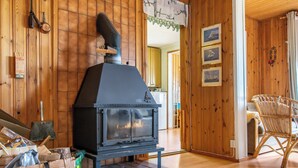 Uma lareira a lenha em um quarto com paredes de madeira e uma cesta de palha no chão.