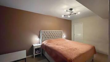 Un dormitorio con cama, mesita de noche y lámpara de techo.