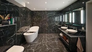Un baño moderno con una bañera independiente, un inodoro y un tocador con espejo.