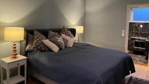 Un dormitorio con una cama, dos mesitas de noche y una mesilla.