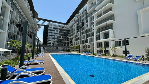 A modern hotel with a central swimming pool, sun loungers, and a multi-story building with balconies. - Bloomfields Studio In Oasis 1 - Masdar (Masdar)