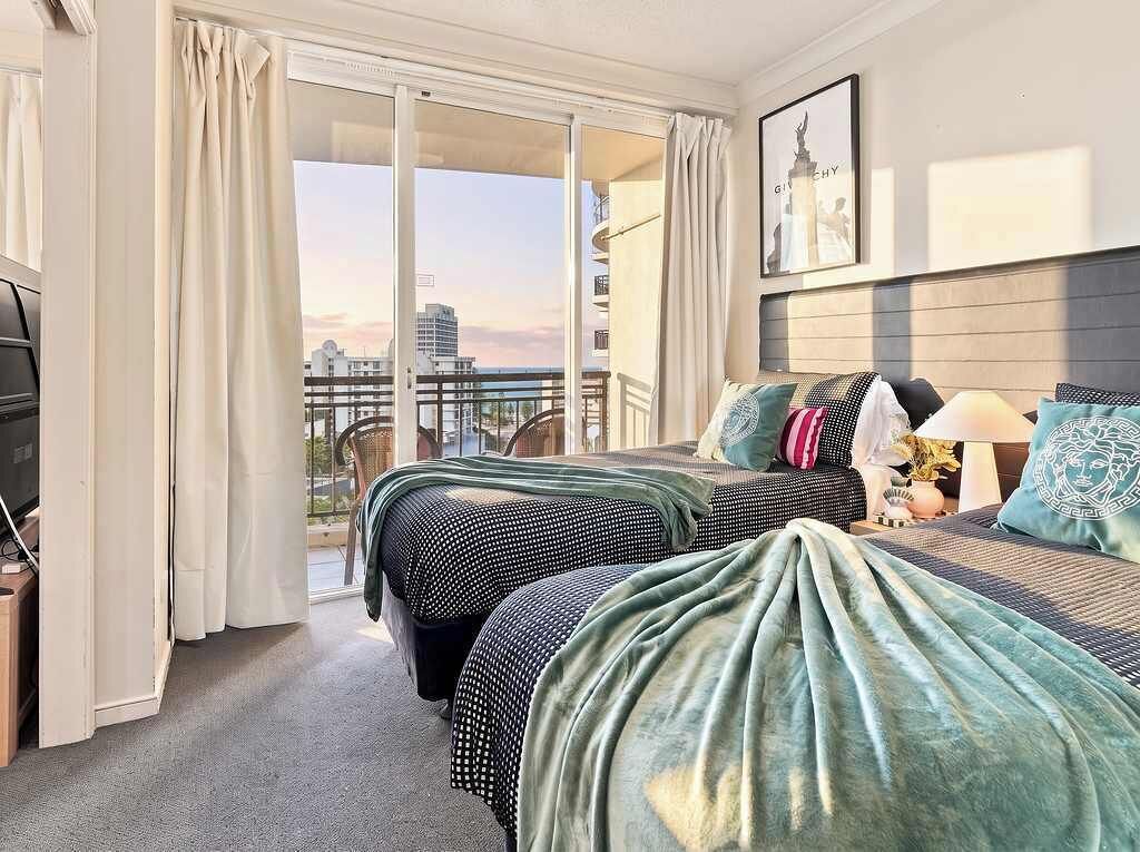 Et hotelværelse med to senge, en balkon og udsigt over byen.