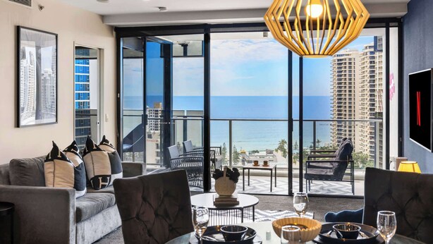 Een moderne hotelkamer met balkon, grote ramen en uitzicht op zee.