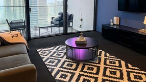 Een moderne woonkamer met een bank, een salontafel, een televisie en een kamerkleed met patroon.