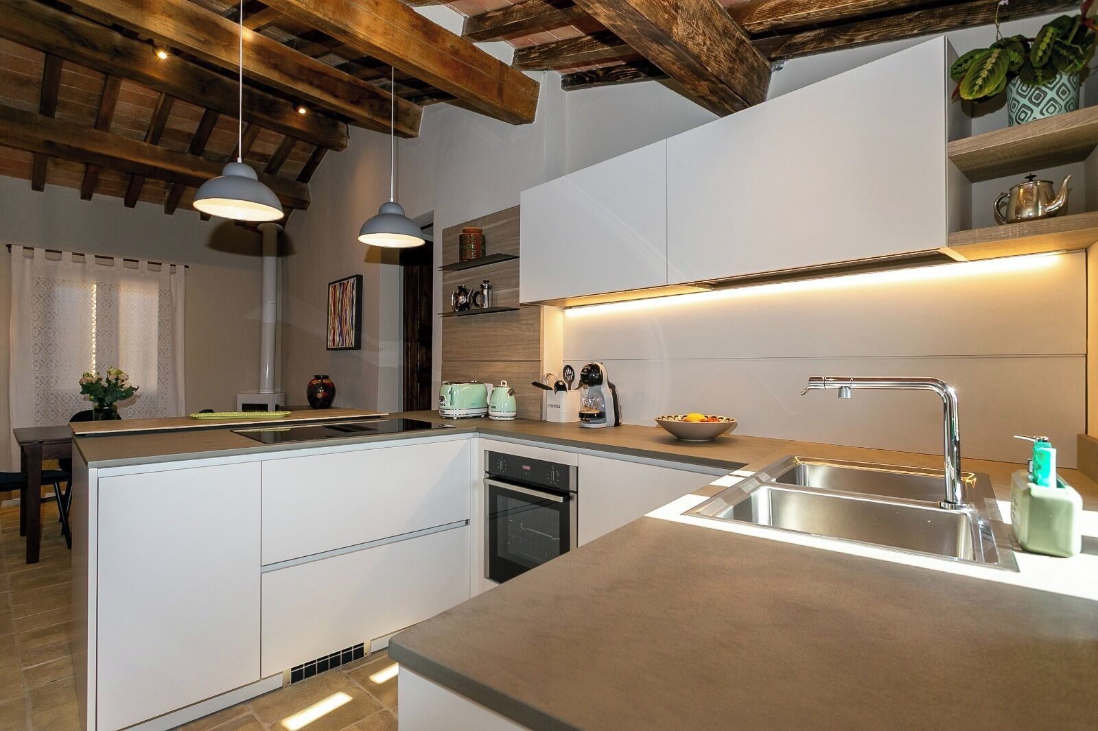 A modern kitchen with a central island, built-in appliances, and pendant lighting.