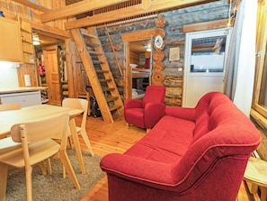 Ein gemütliches Blockhaus-Interieur mit Essbereich, einem roten Sofa und einer Holztreppe.