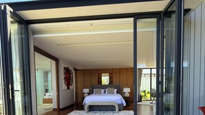 Quarto moderno com uma cama grande, portas de vidro deslizantes e vista para o exterior.