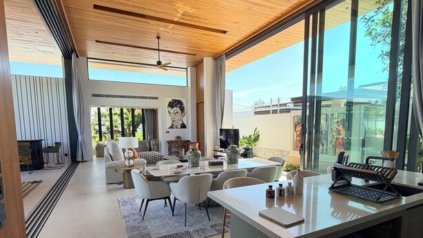 Uma sala de estar moderna e integrada, com mesa de jantar, sofás e ilha de cozinha.