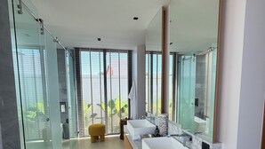 A modern bathroom with a glass shower enclosure, dual sinks, a large mirror, and a view of greenery outside. - BRAND-NEW LUXURY VILLA IN THE BOTANICA FORESTIQUE RESIDENCE IN PHUKET, NEAR THE GOLF COURSE (Choeng Thale)