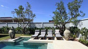 A clear swimming pool with lounge chairs, surrounded by potted plants and a white wall. - BRAND-NEW LUXURY VILLA IN THE BOTANICA FORESTIQUE RESIDENCE IN PHUKET, NEAR THE GOLF COURSE (Choeng Thale)