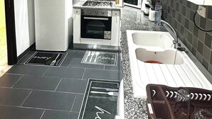 Una cocina compacta equipada con refrigerador, estufa, horno, microondas y pileta.