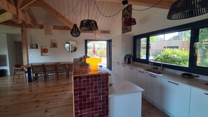 Eine moderne Küche mit Holzbalken, einem großen Fenster und einer zentralen Kochinsel.