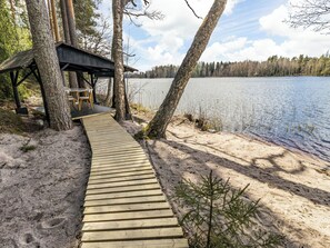 Puinen terassi, joka johtaa katettuun oleskelualueelle järven rannalla.