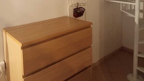 Una habitación con un aparador de madera, un radiador y una escalera en espiral blanca.