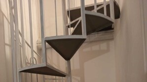 Una escalera de caracol con barandillas metálicas y piso alfombrado.