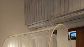 Una cama individual con dosel, una ventana pequeña y techo de madera.