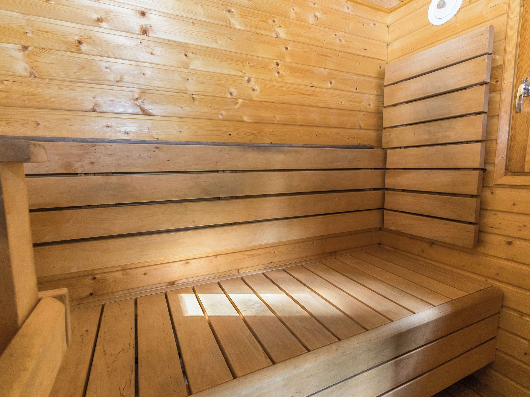 Un sauna en bois avec des lattes horizontales, un banc et une porte.