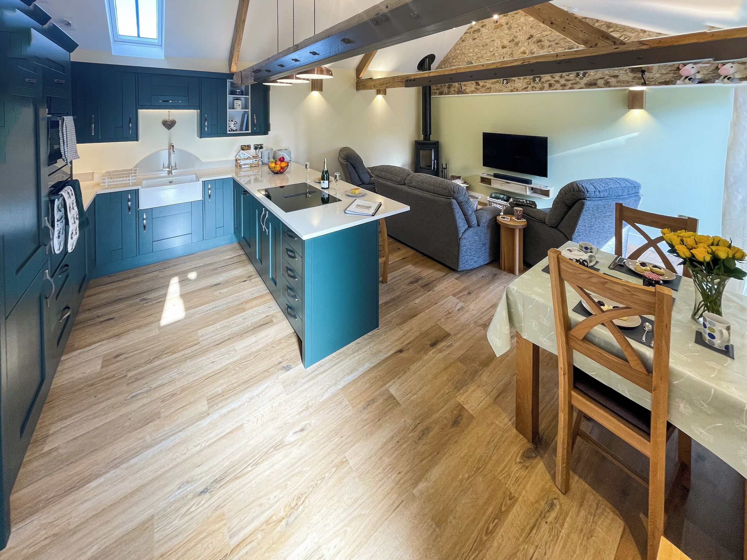 Una cocina moderna con una isla central, una zona de comedor con mesa y sillas, y un rincón de estar acogedor con sofá y televisor.
