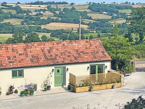 Ein eingeschossiges Haus mit rotem Ziegeldach, einer grünen Tür und einer kleinen Veranda mit Holzgeländer.