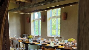 Een eetgedeelte met een rustiek houten plafond, grote ramen en een gedekte tafel.