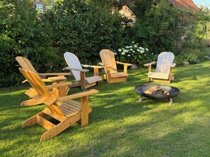 Un conjunto de sillas Adirondack dispuestas alrededor de una fogata en un césped.