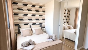Ein Schlafzimmer mit einem Bett, einem Spiegel und einer Wand mit geometrischem Muster.