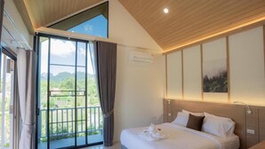 Une chambre avec un grand lit, une vue sur l’extérieur par une porte coulissante et un plafond recouvert de lambris en bois.