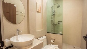 Une salle de bain moderne avec un lavabo rond, des toilettes et une douche à parois de verre.