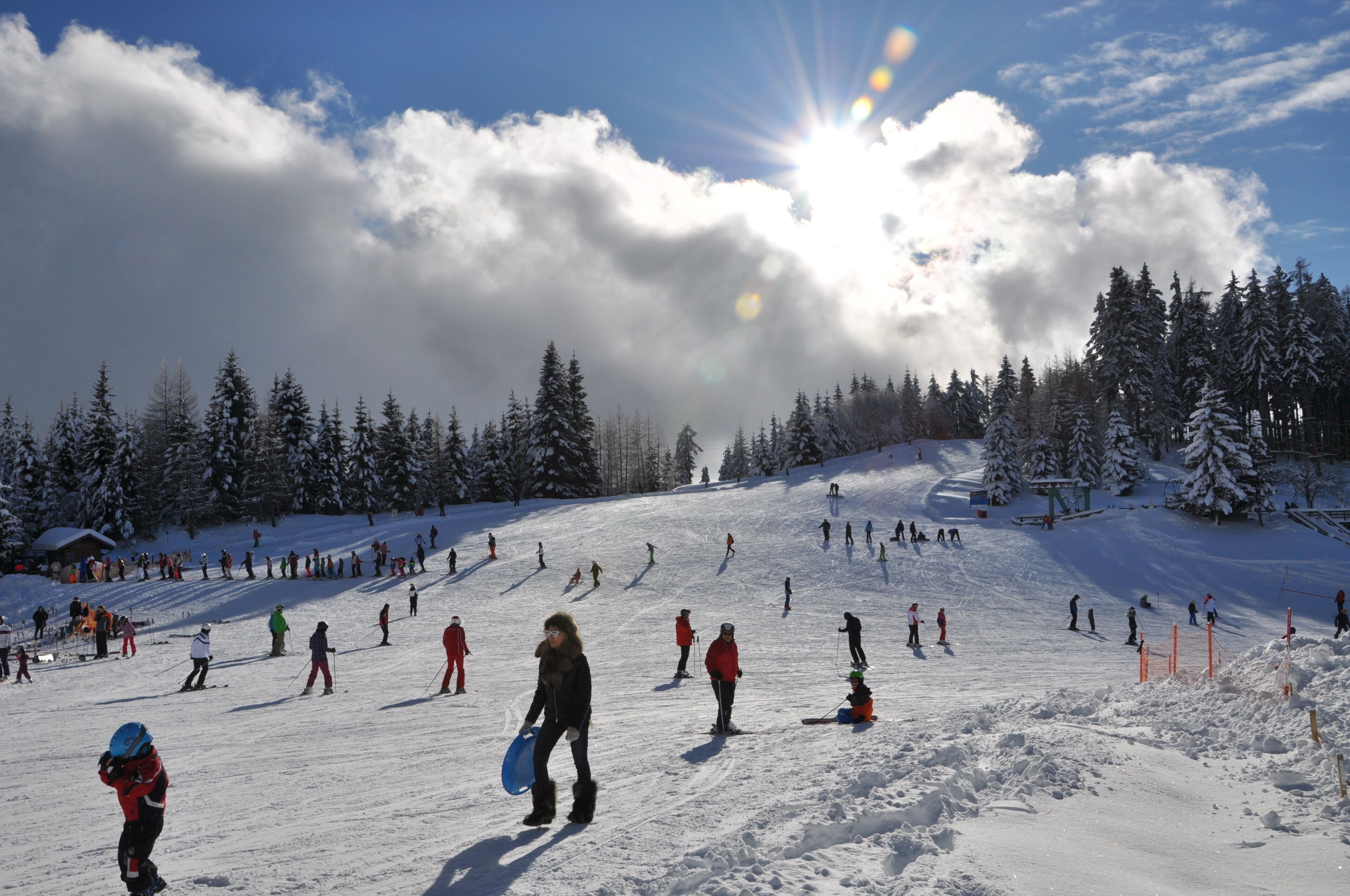 A snowy ski slope with skiers and a clear sky.