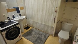 A compact bathroom with a washing machine, a sink, a toilet, and a shower curtain. - I'm renting out my apartment, located 15 meters from the Canal Saint-Martin in the 10th arrondissement. (Paris)