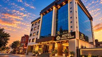 A hotel with a modern glass facade, a prominent entrance with a staircase, and a sign reading 'HOTEL CRYSTAL RETREAT'.