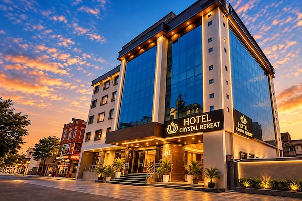 Un hotel con fachada moderna de vidrio, una entrada destacada con una escalera y un cartel que dice 'HOTEL CRYSTAL RETREAT'.