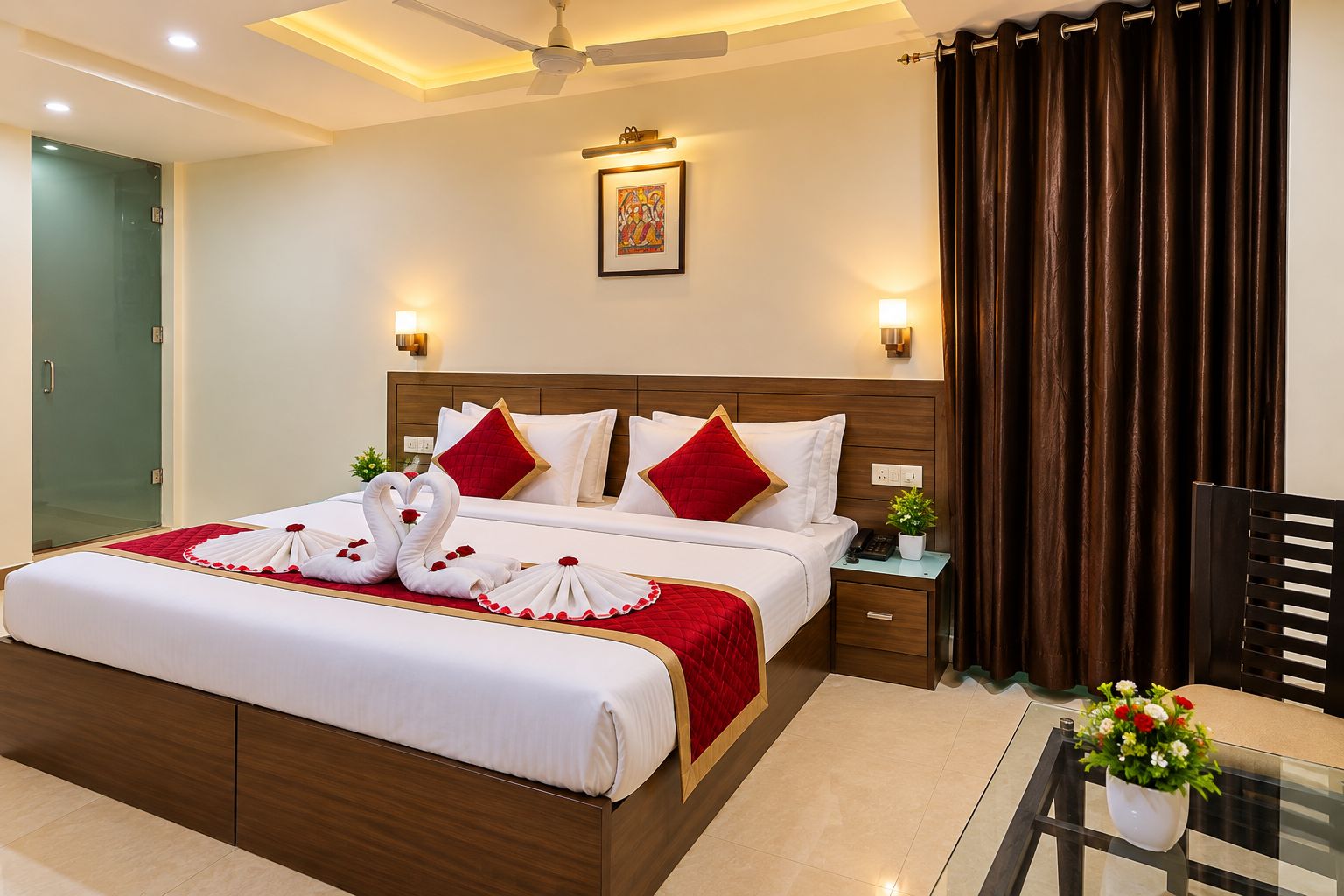 A hotel room with a bed, bedside tables, a nightstand, a chair, a glass table with a vase, and a ceiling fan.