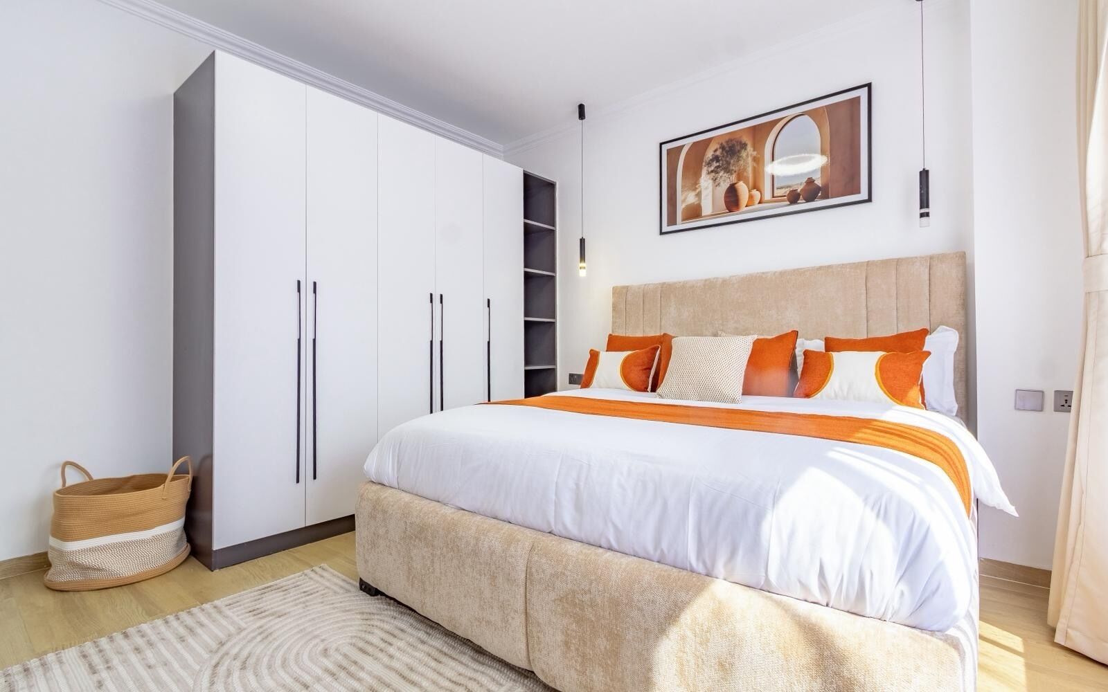 Un dormitorio con una cama, un armario, una lámpara colgante y un cuadro en la pared.
