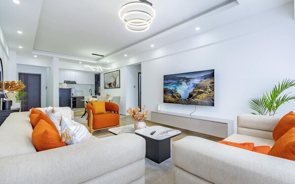 Una sala de estar moderna con un juego de sofá, una mesa de centro y un televisor montado en la pared.