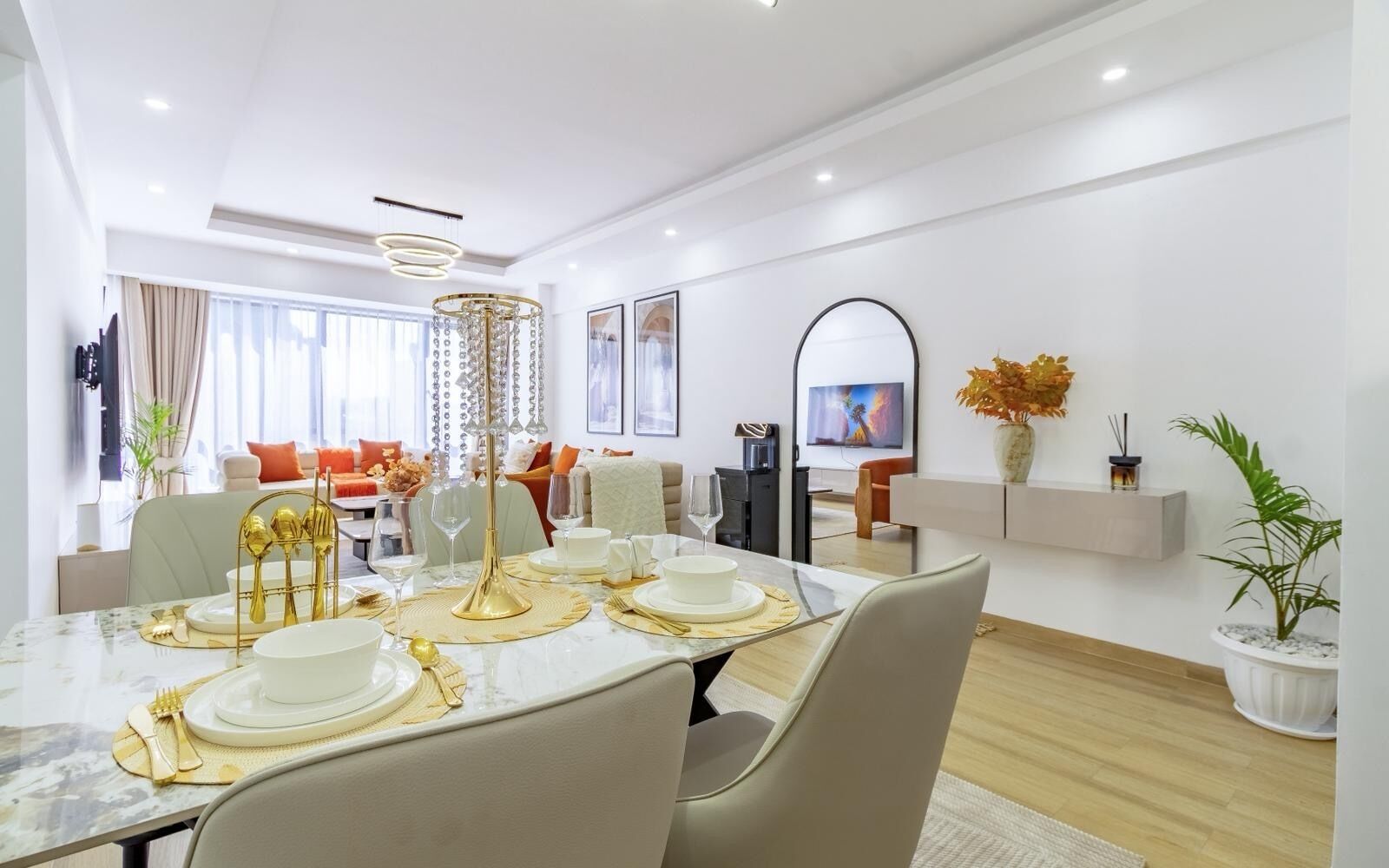 Une salle à manger moderne avec une table en marbre, des éléments décoratifs dorés et un lustre.