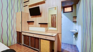 A room with a wooden vanity, a flat-screen TV, a mirror, and a sink. - Pelangi Guest House Cozy Stay (Curug)