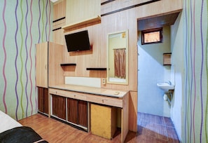 Una habitación con tocador de madera, televisor de pantalla plana, espejo y lavamanos.
