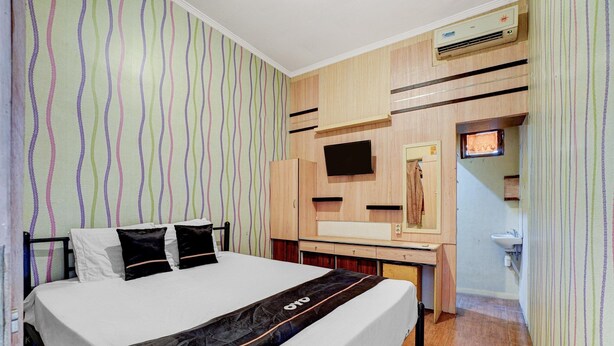 A hotel room with a bed, a desk, a television, and a bathroom. - Pelangi Guest House Cozy Stay (Curug)