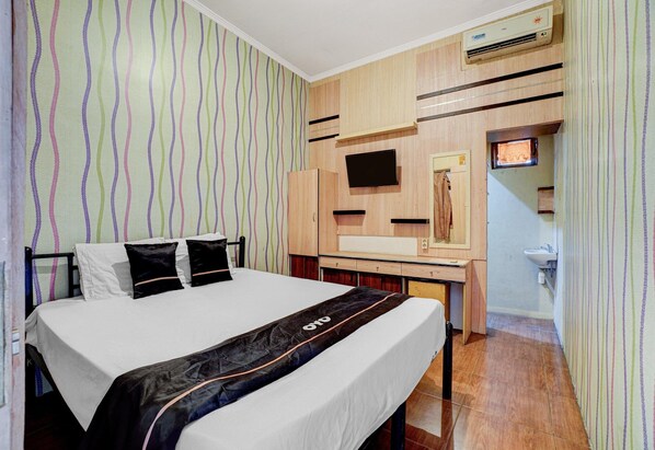 Una habitación de hotel con cama, escritorio, televisión y baño.