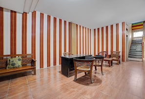 Una habitación con papel tapiz a rayas, un banco de madera, un escritorio con sillas y una escalera.