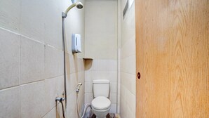 A small, narrow bathroom with a toilet, shower, and hand dryer. - Pelangi Guest House Cozy Stay (Curug)