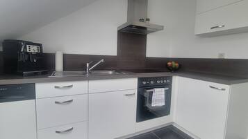 A modern kitchen with a dishwasher, oven, and a coffee maker.