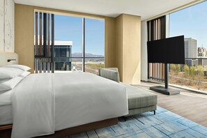 Ein modernes Hotelzimmer mit einem großen Bett, einem Flachbildfernseher und Blick auf die Stadtlandschaft.